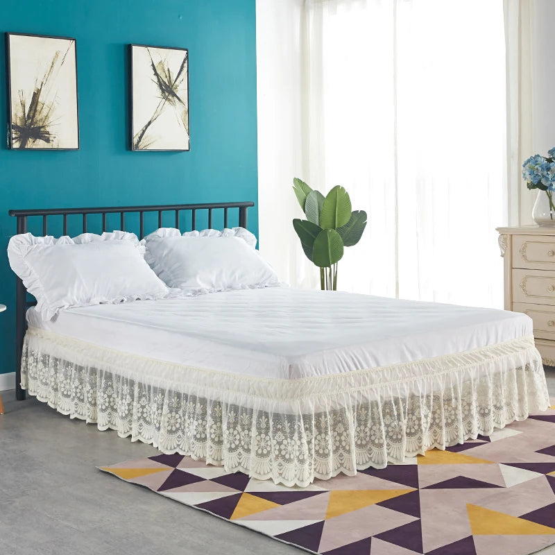 A white bed with a ruffled lace skirt and white bedding set against a teal wall.