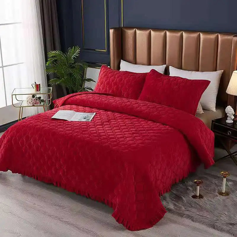 A vibrant red quilted velvet bedspread with a textured pattern is displayed on a bed in a modern bedroom setting.
