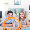 A family of three is pictured with a DIY stunt racing car track set featuring an orange loop and dual-lane races on a wooden 