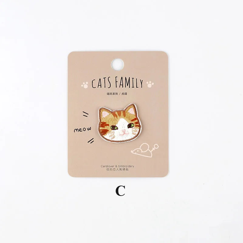 A beige iron-on patch featuring an embroidered orange and white cat face with the text Cats Family and meow.