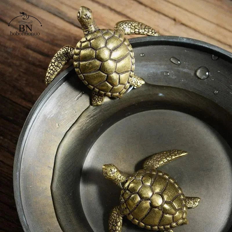 A solid copper turtle figurine is placed on a round metal dish.