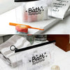 A clear transparent toiletry bag with a hanging hook filled with various bath products like lotions and soaps.