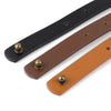 A close-up view of a black and tan PU leather crossbody bag strap with brass hardware.