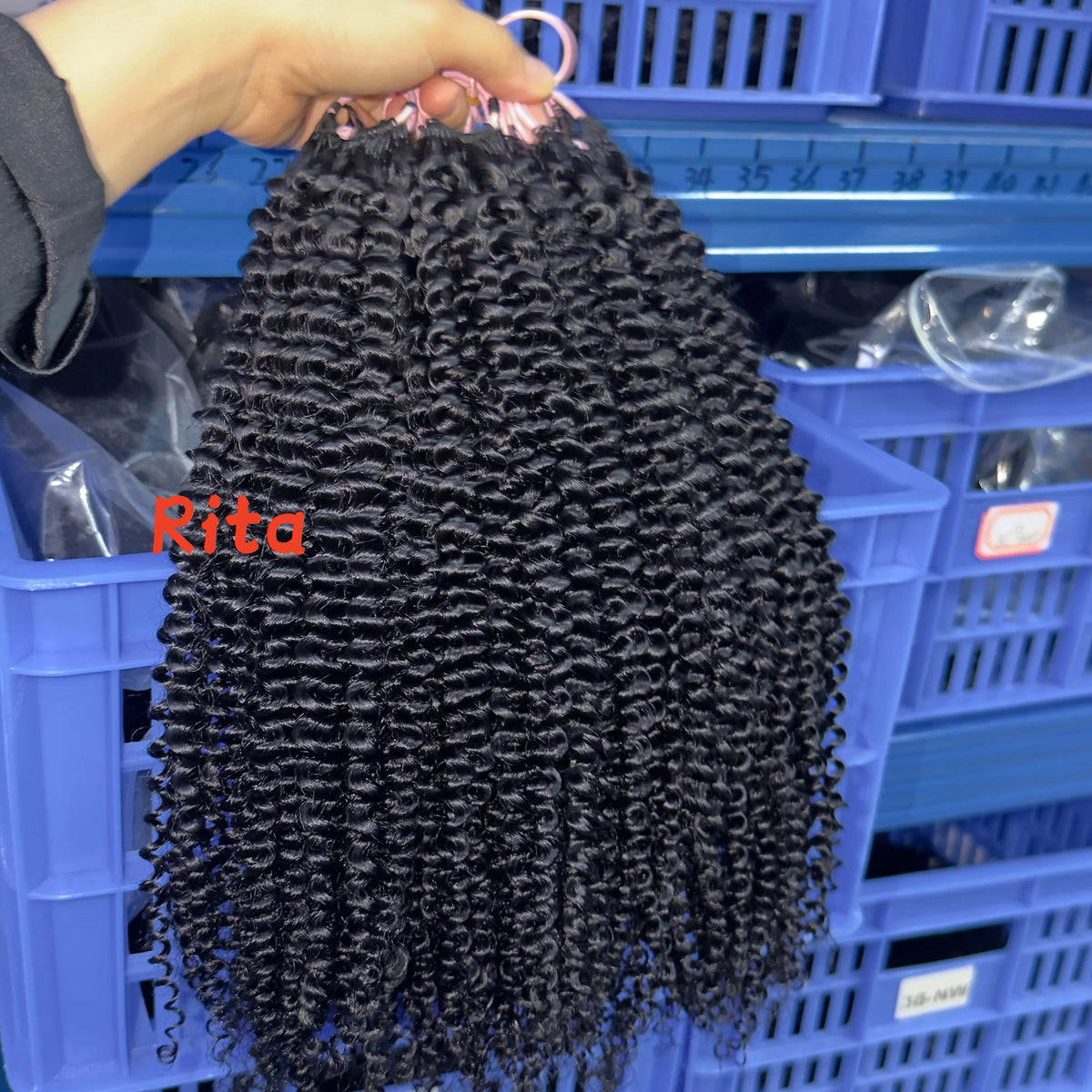A bundle of black deep wave knotless crochet braids is being held over a blue plastic storage basket.