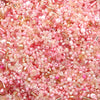 A close-up view of mixed pink and rose glass seed beads for jewelry making and crafts.