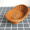 A round, handwoven wicker serving basket in natural brown color resting on a gray and white checkered surface.
