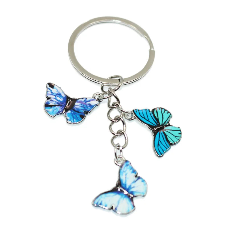 A colorful butterfly keychain charm with blue and white wings attached to a silver ring.