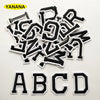 A collection of black embroidered alphabet patches, including letters A through D, scattered on a white background.