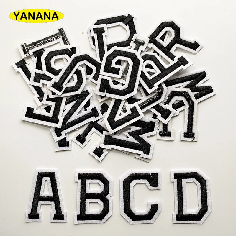 A collection of black embroidered alphabet patches, including letters A through D, scattered on a white background.