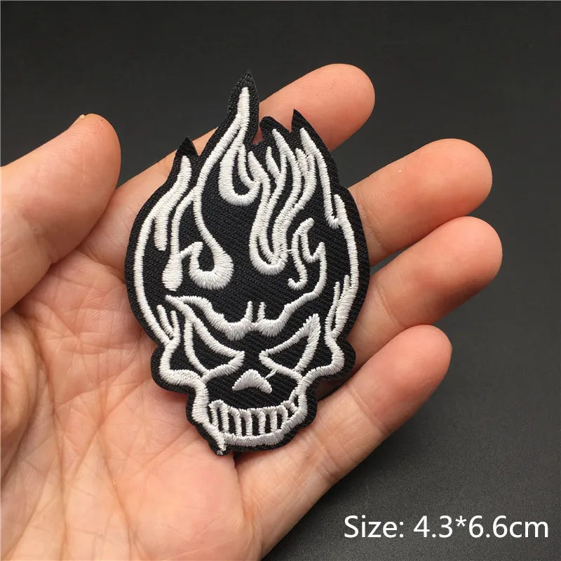 Black and white embroidered punk skull patch design being held in a hand.