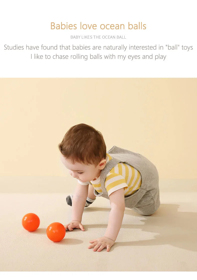 A baby is playing with small orange balls on a light surface.