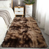 Extra large brown Nordic fur rug placed in a bedroom setting next to a wooden nightstand and white bedding.