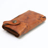 A brown vintage cowhide leather bi-fold wallet with a brass stud closure.
