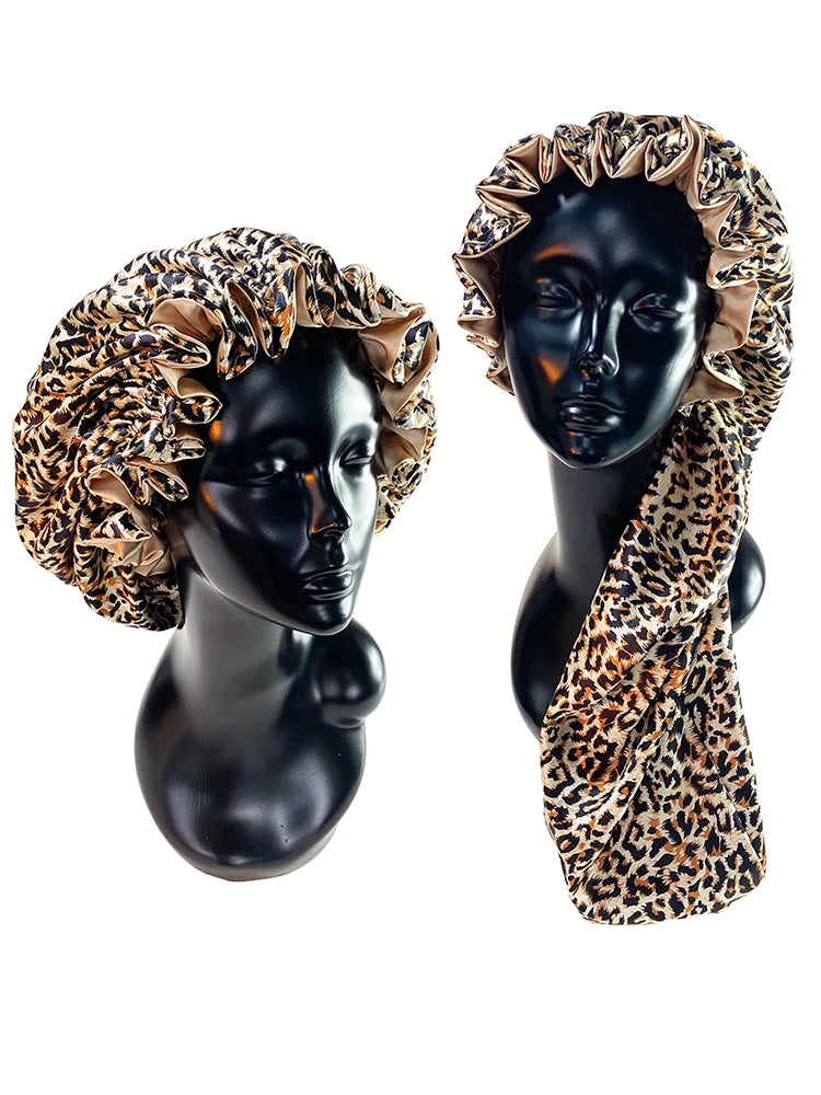 A black mannequin head wearing a double-layer satin hair bonnet with an adjustable band featuring a leopard print fabric.