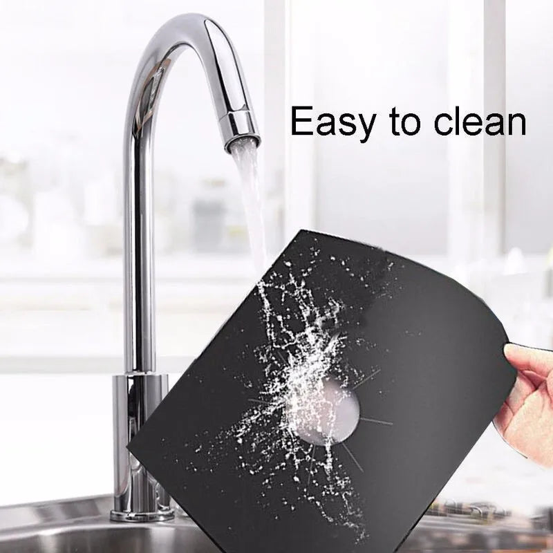 A black reusable non-stick gas stove protector mat is being rinsed under a faucet.