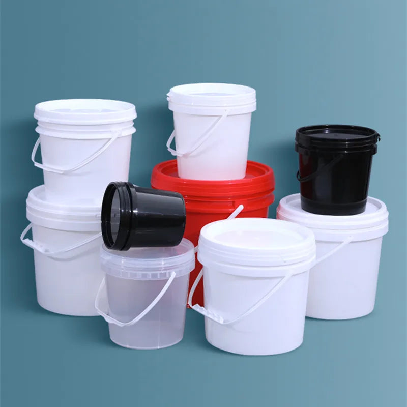 A collection of white, black, and red plastic buckets with leakproof lids arranged on a teal surface.