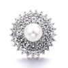 A close-up of a round, brilliant diamond-encrusted metal snap button with a central pearl.
