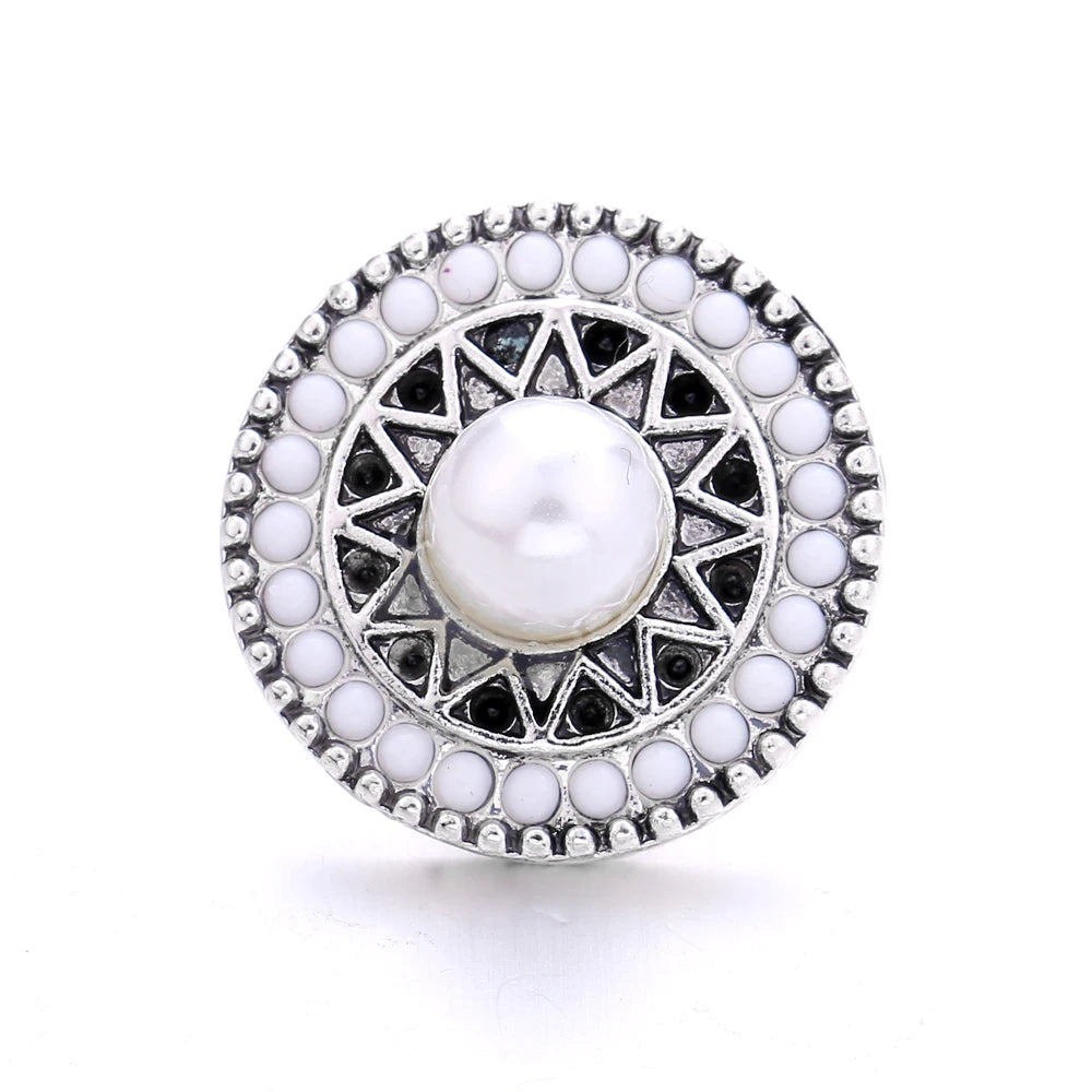 Silver metal snap button with a white pearl center surrounded by small white and black stones