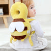 A yellow stuffed bee head protector backpack worn by a toddler, sitting on a gray rug.