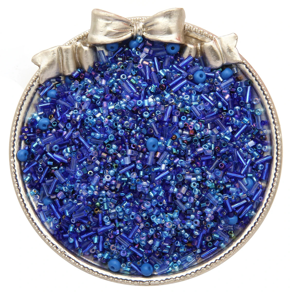 A silver-rimmed dish filled with mixed blue and purple glass seed beads for jewelry making