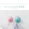 Pink and teal suction cup hooks mounted on a white surface, demonstrating a strong vacuum seal.