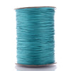 A spool of teal waxed cotton cord used for jewelry making.
