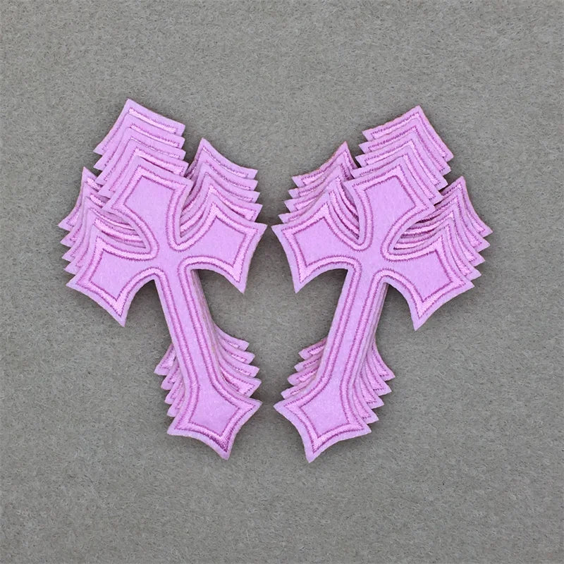 A set of ten embroidered pink cross iron-on patches displayed against a gray background.