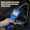 A hand holds a blue digital engine oil and brake fluid quality tester with an LED display, positioned near a vehicle engine c