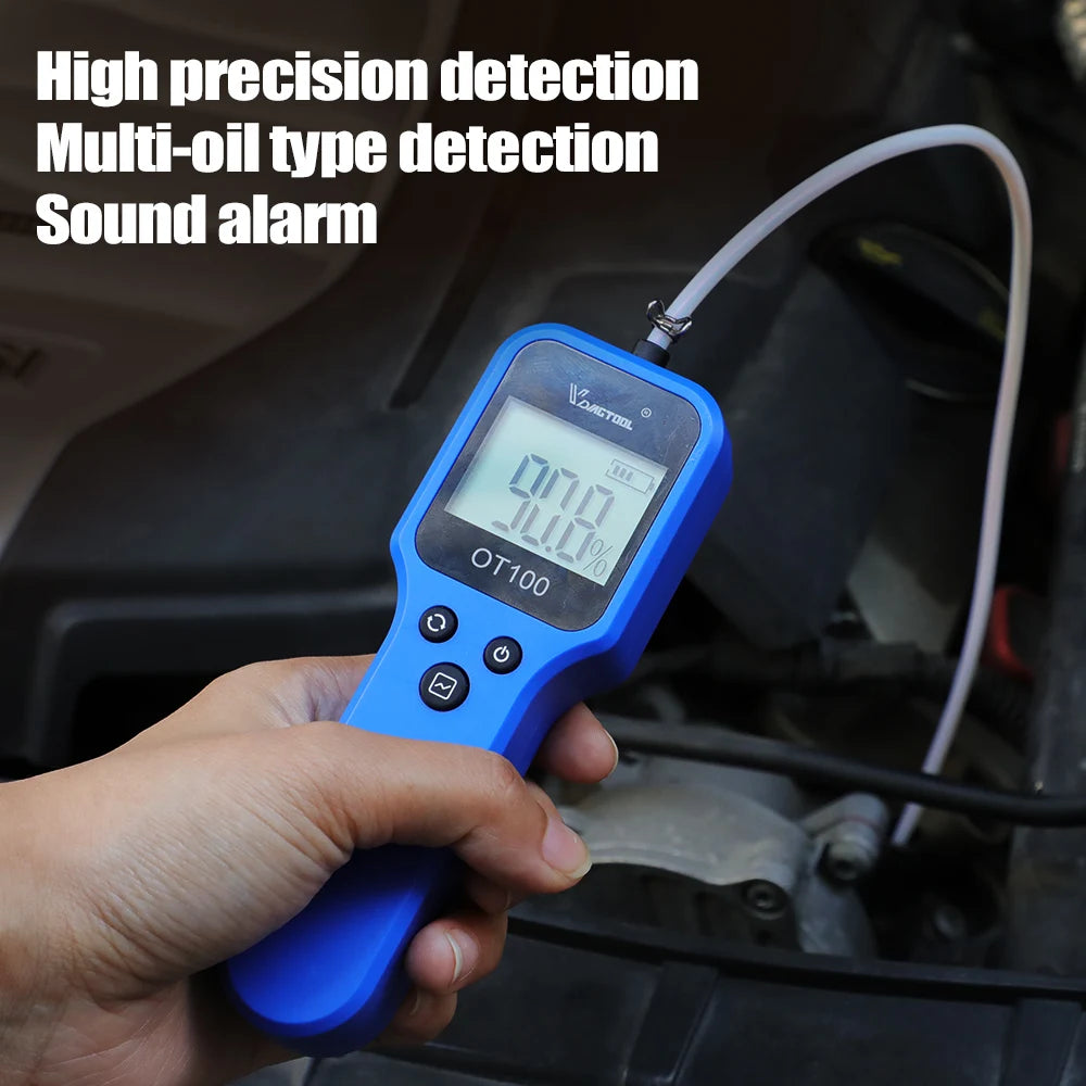 A hand holds a blue digital engine oil and brake fluid quality tester with an LED display, positioned near a vehicle engine c