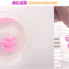 A pink magical water-growing ocean animal toy is visible in a clear glass of water.