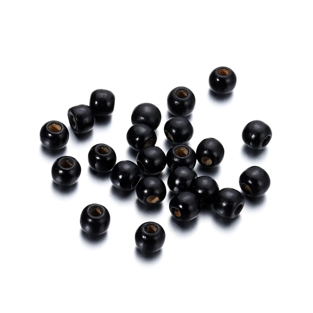 A pile of natural wooden spacer beads in black, arranged on a white background.
