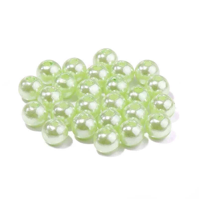 A cluster of round, pale green ABS imitation pearl beads for jewelry making.