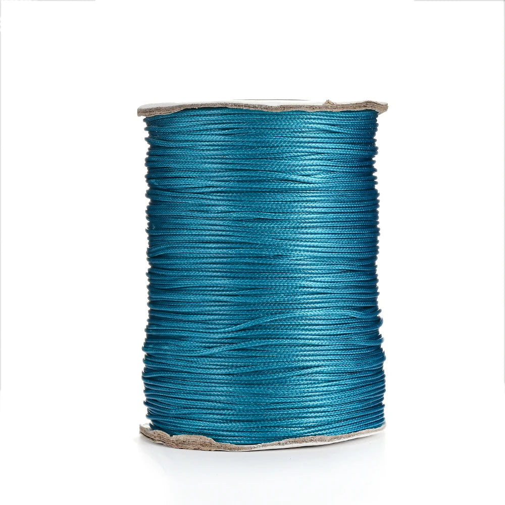 A spool of teal waxed cotton cord used for jewelry making.
