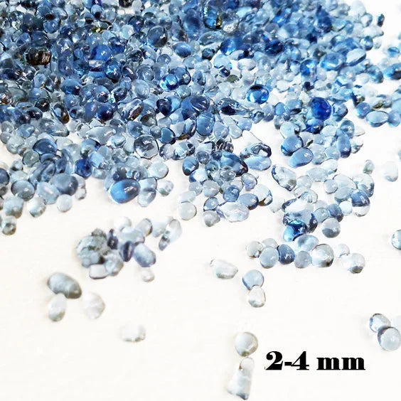 A pile of small, translucent blue decorative stone pebbles for terrariums and aquariums.