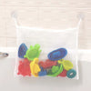White mesh storage hammock filled with colorful plastic toys hanging on a kitchen backsplash.