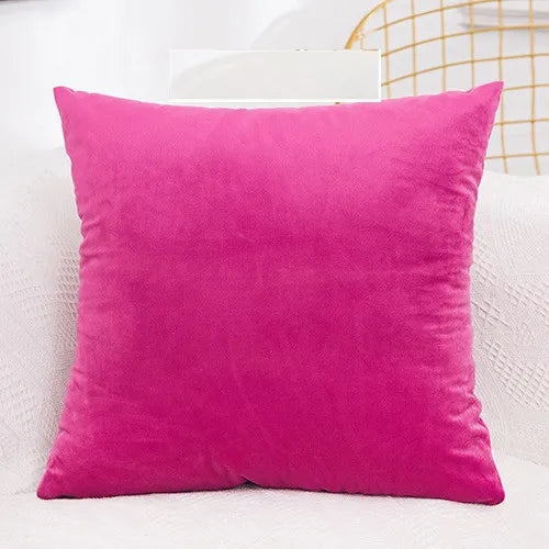 A vibrant magenta velvet decorative cushion cover resting on a white surface.
