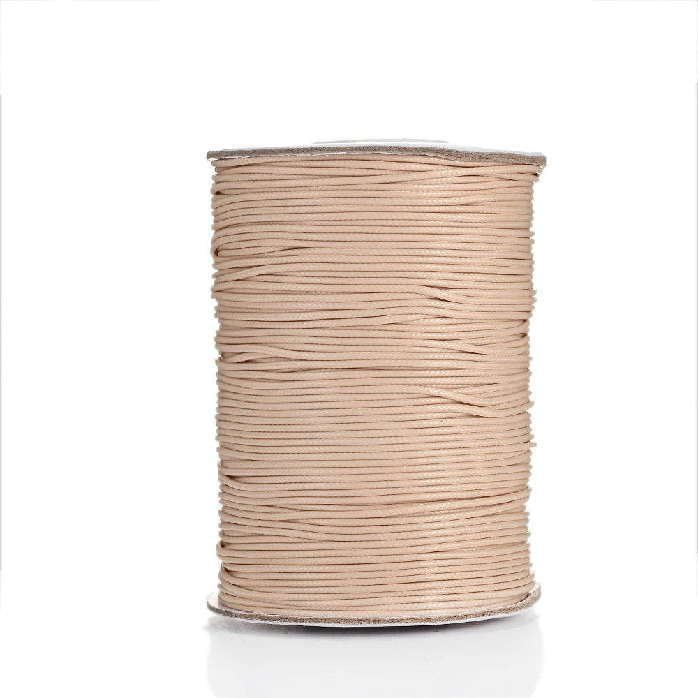 A spool of light beige waxed cotton cord used for jewelry making.
