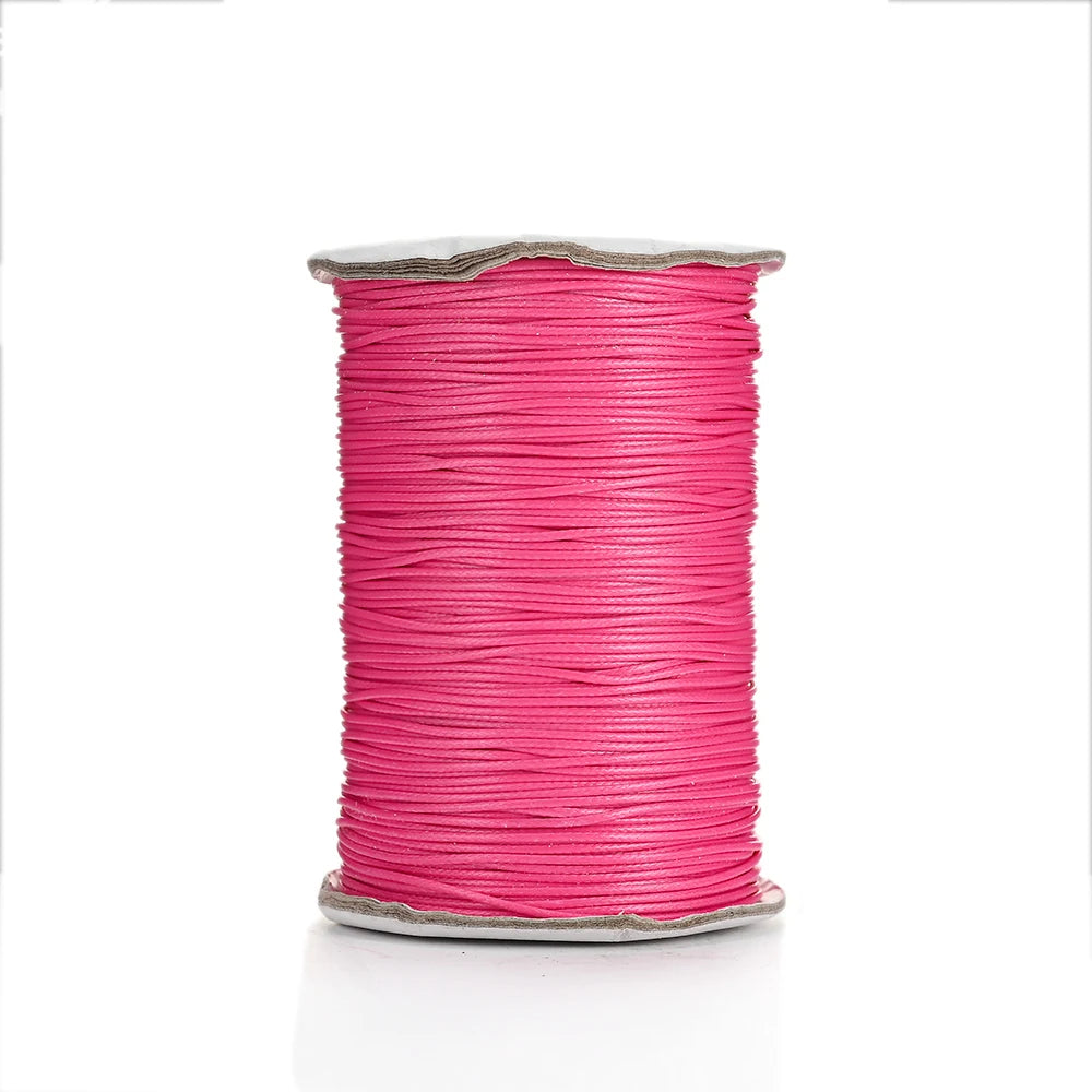 A spool of bright pink waxed cotton cord used for jewelry making.