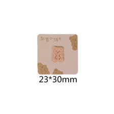 A square beige iron-on patch featuring a light brown embroidered bear design.