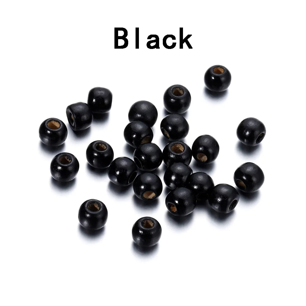 A pile of small, black wooden spacer beads for jewelry and crafts.