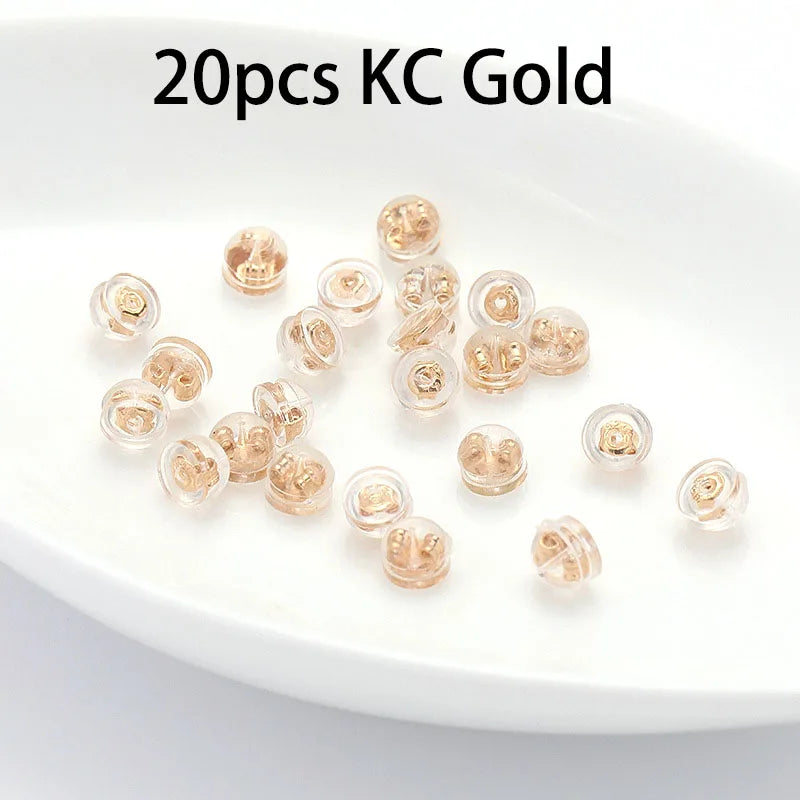 20 pieces of gold silicone rubber ear back stoppers with copper rings displayed on a white plate.