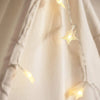 A soft, light-colored fabric tent with string lights and star decorations hanging indoors.