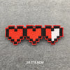 A set of embroidered iron-on patches shaped like hearts in red, black, and white.