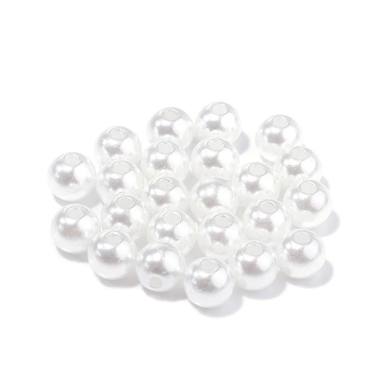 A cluster of small, round white imitation pearl beads for jewelry making.