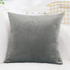 A solid gray velvet decorative cushion cover resting on a white surface.