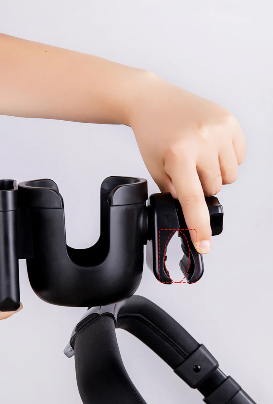 A hand is adjusting the cup holder mechanism on a black universal stroller cup and phone holder device.