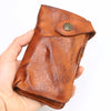 A brown vintage cowhide leather bi-fold wallet is held in a hand, showing the texture and stitching.