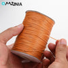 A hand is holding a spool of orange waxed cotton cord for jewelry making.