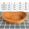 A close-up view of a round, handwoven wicker serving basket with a natural brown color.