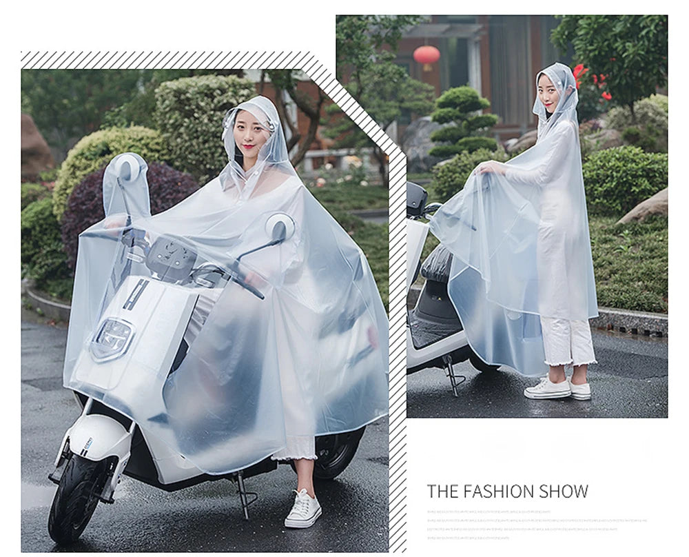 A woman wearing a transparent waterproof motorcycle rain poncho with a hood riding a motorcycle outdoors.